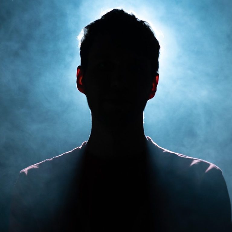 Silhouette einer Person vor einem Hintergrund aus Rauch und blauem Licht